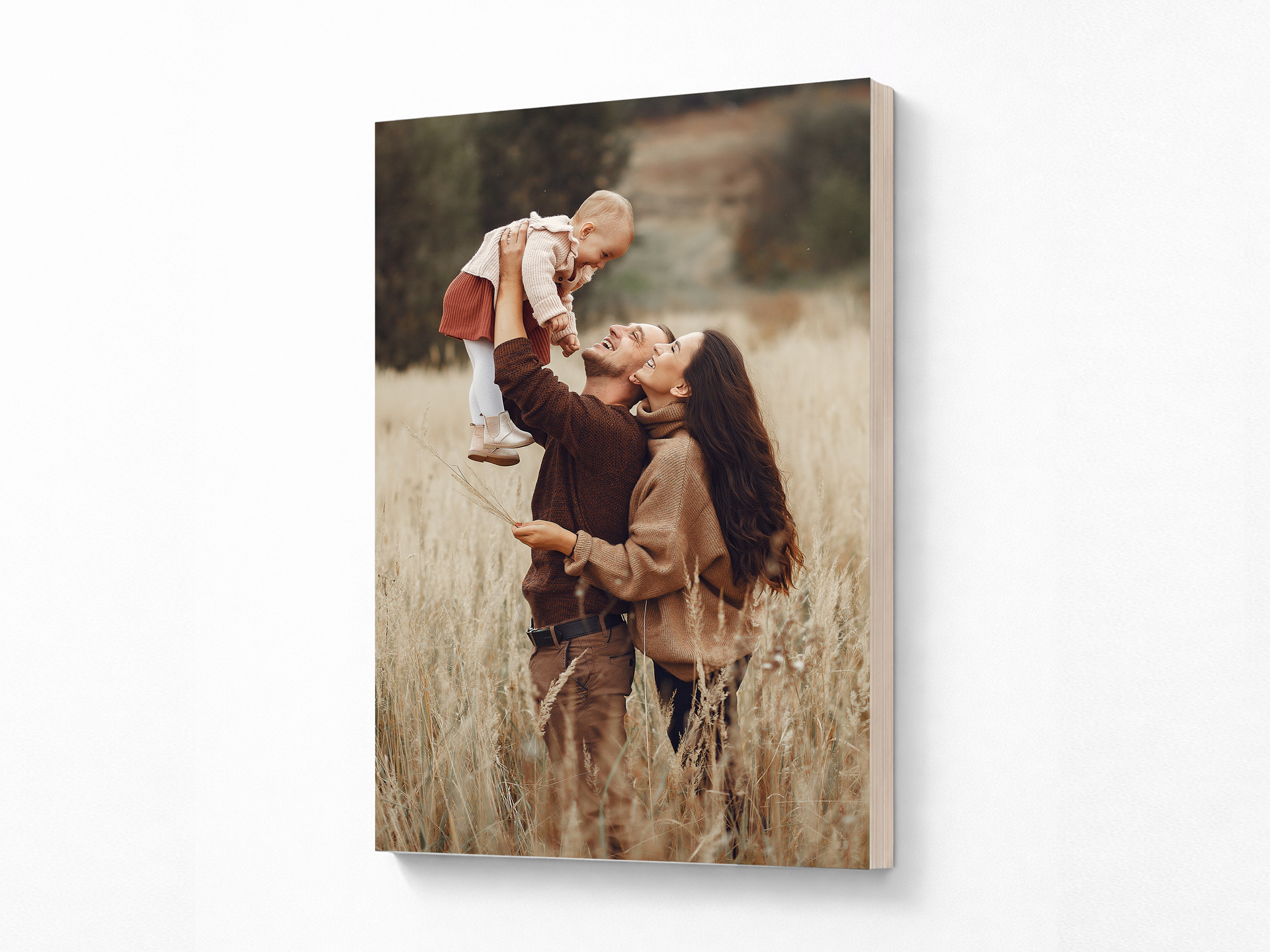 A wall-mounted wood print featuring a married couple happily holding their child