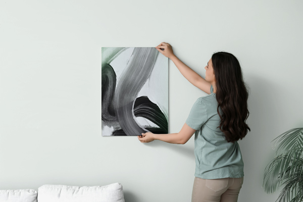 An image of a woman positioning an abstract PVC art print on the wall.