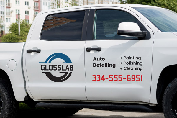 An auto detailing business's logo, services and phone number adhered to the side of a company car.