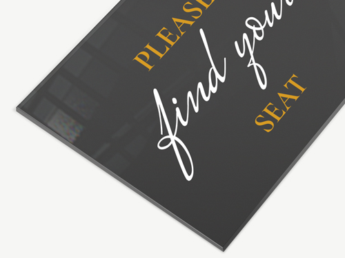 Black transparent wayfinding sign asking attendees to find their seats.