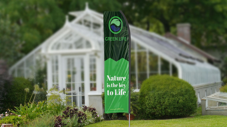Green Life econo feather flag in green and black set up in the garden.