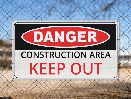 Hanging danger warning mesh banner reading construction ares keep out