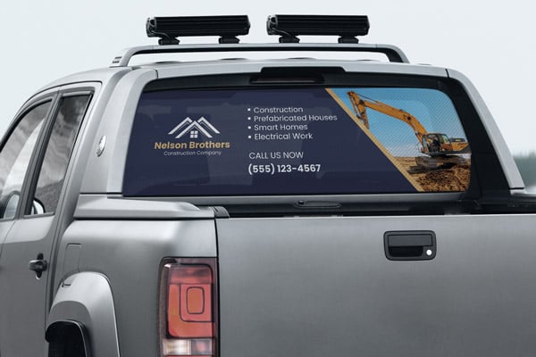 A perforated truck window decal showcasing the services of a construction company as well as its logo and contact information.