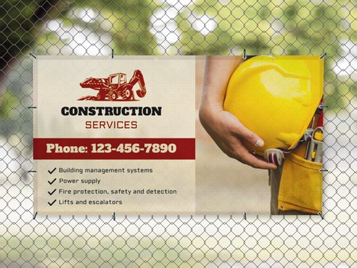 Hanging mesh banner on a fence reading construction services