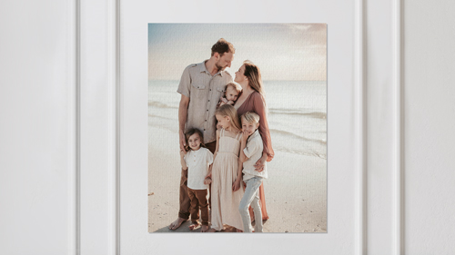 A canvas print of family portrait showing parents with two children on beach.