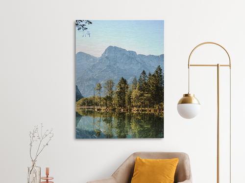 A brushed aluminum photo print showing a beautiful natural landscape of a lake surrounded by trees and mountains.