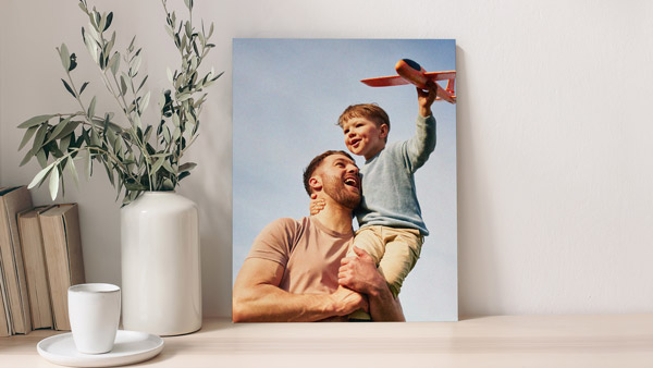 A foam board print of a father-son duo having fun outside with an RC plane.