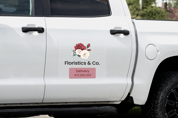 A white truck with a clear florist business decal on its rear right door.