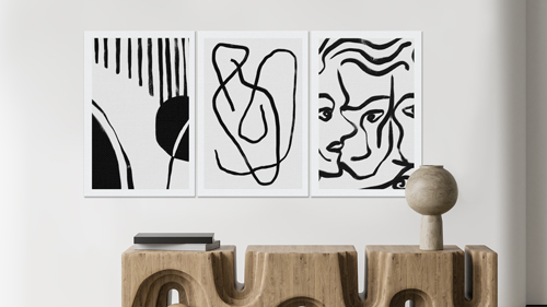 Three abstract black and white canvas prints with geometric patterns hung on wall above shelf.