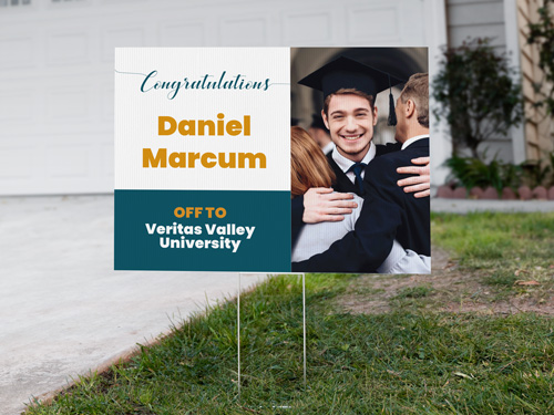 A teal and white yard sign with the image of a young graduate set up on the front yard.