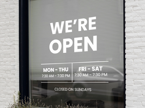 Informative vinyl lettering on the store's window reading We're Open.