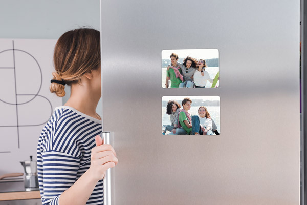 Two photos of a family on vacation printed on magnets and attached to a refrigerator door.