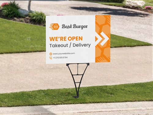 A burger joint yard sign set up outside on a spider stake and indicating that the restaurant is open for business.