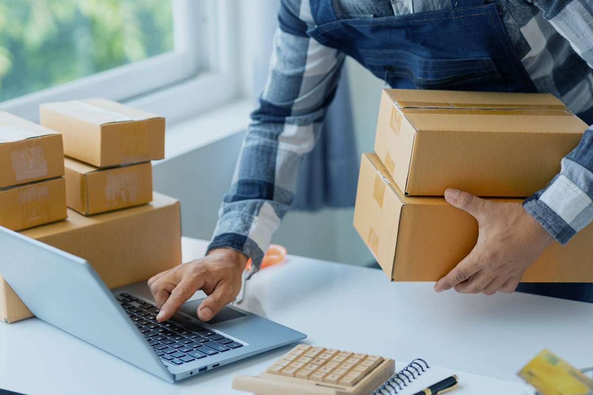 An image of a person processing packages using a computer.