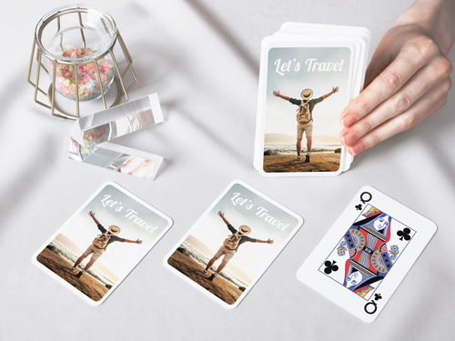 Stylish playing cards with a 'Let's Travel' design on the back, alongside a fully revealed Queen of Clubs
