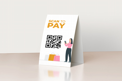 White table tent displaying QR code payment option with colorful person illustration.