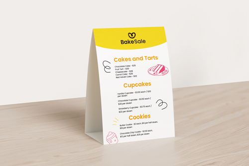 White table tent with yellow top showing cupcakes and cookies menu.