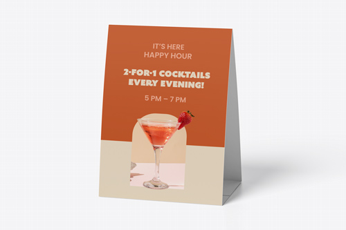 Orange and beige table tent advertising 2-for-1 cocktails happy hour from 5-7 PM