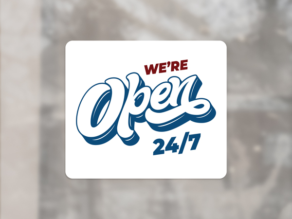 White business operating hours window cling reading We're Open 24/7.