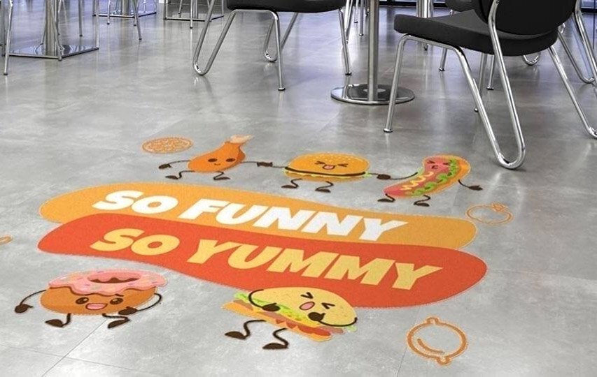 Colorful floor decal with cartoon food characters and So Funny So Yummy text design.